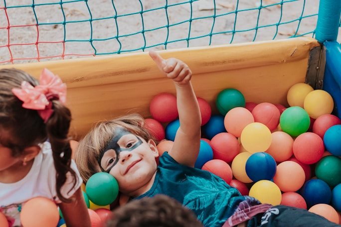 A smiling child with glasses playing in a ball pit