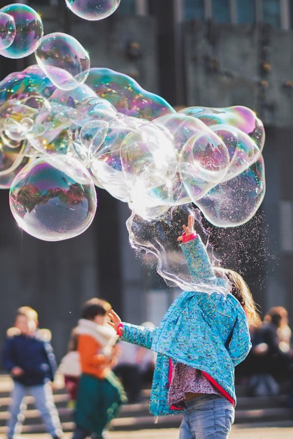 A child playing with giant soap bubbles in a park