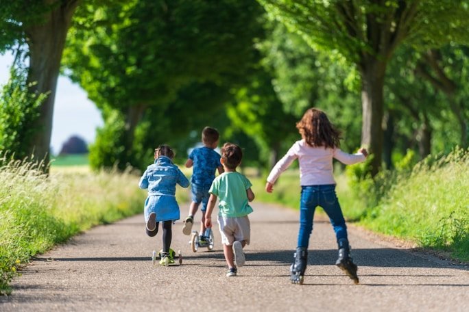 Children running along a tree-lined path