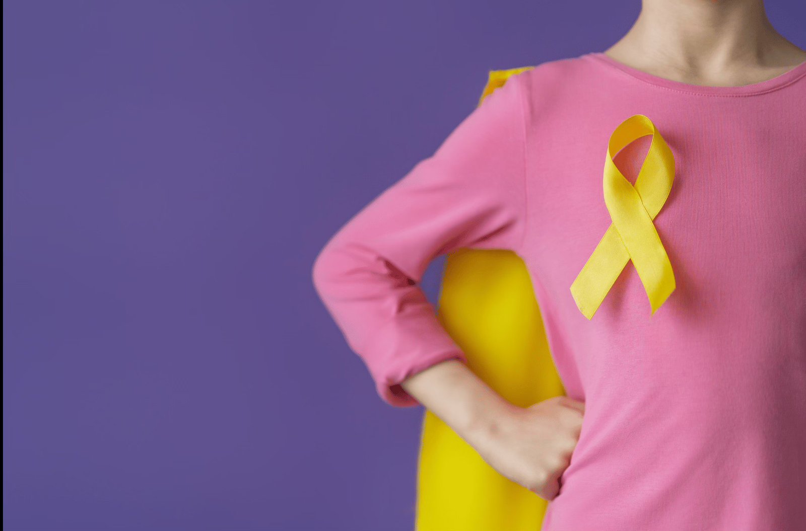 A child wearing a yellow childhood cancer awareness ribbon