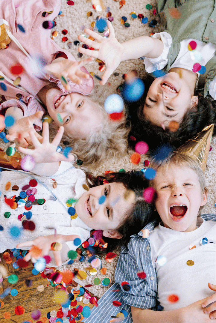 Children lying on the floor, laughing and playing with confetti